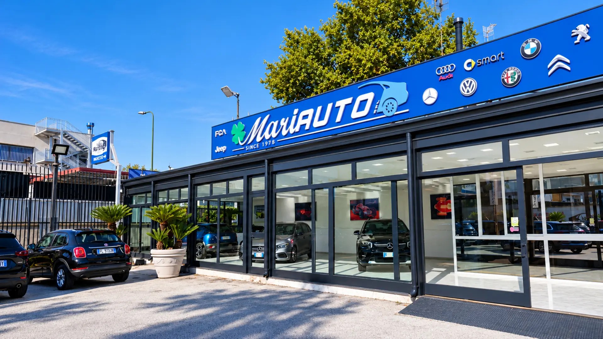 Ingresso dello showroom Mariauto con le auto in esposizione nel piazzale